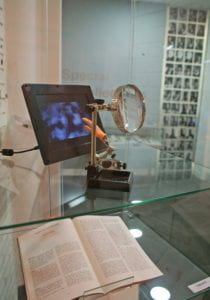 book, magnifying glass, digital image display and plastic hand in glass display case