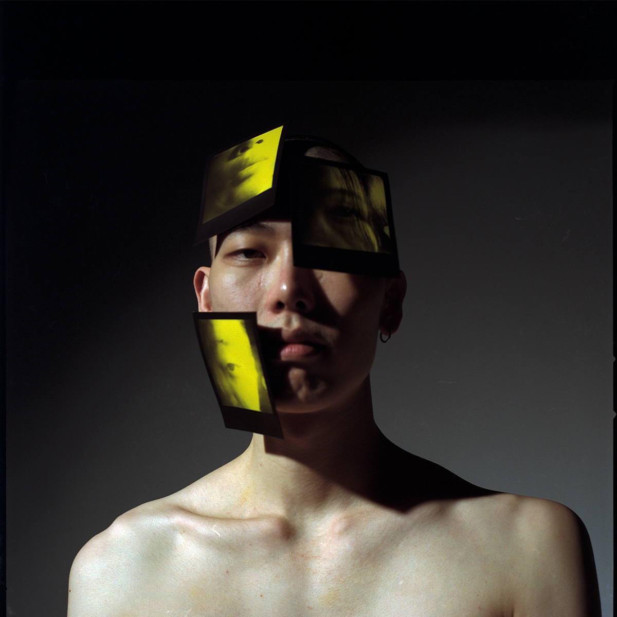 A photograph of a person wearing three yellow polaroids of another person on their face.