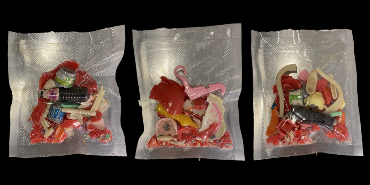A picture of three vacuum sealed bags holding various plastic pieces, against a black background.