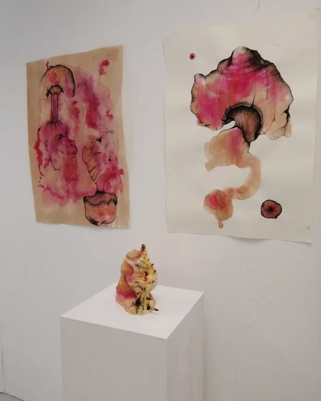 A ceramic shell beneath two abstract watercolour drawings on paper.