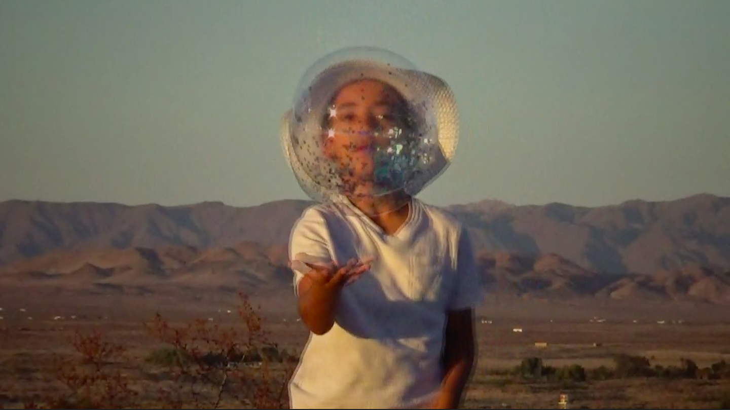 An image of a child lifting a glittery bubble in a desert landscape.
