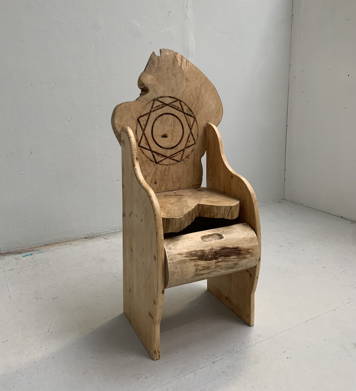 A wooden throne with a 9-sided star carved into its headrest.