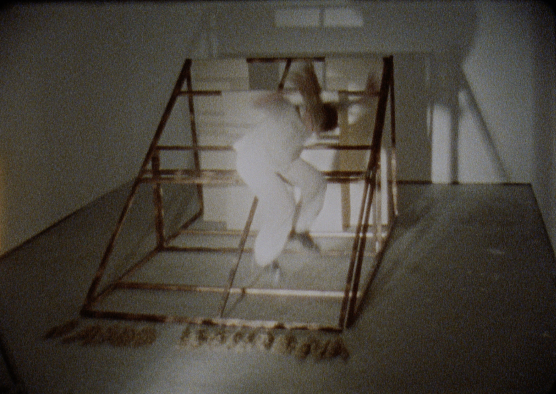 An image of a person dressed in white jumping onto a wooden, wedge-shaped object.