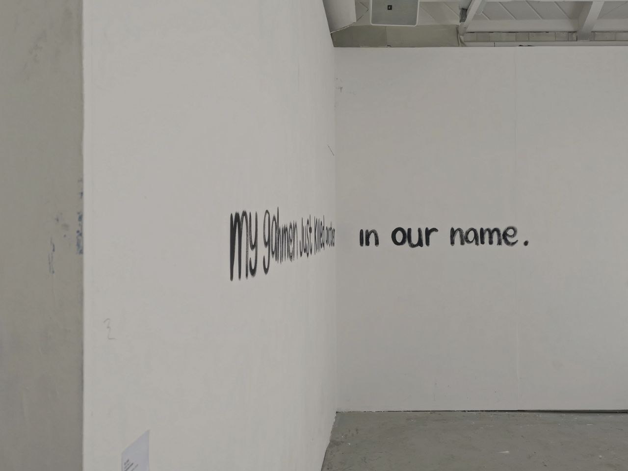 A photo of black writing on a white wall.