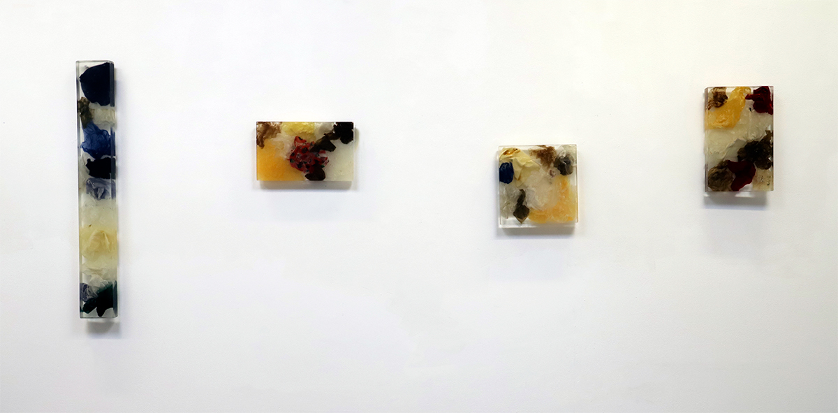 a photo of several used napkins encased in a square of clear resin, hung on a white wall.