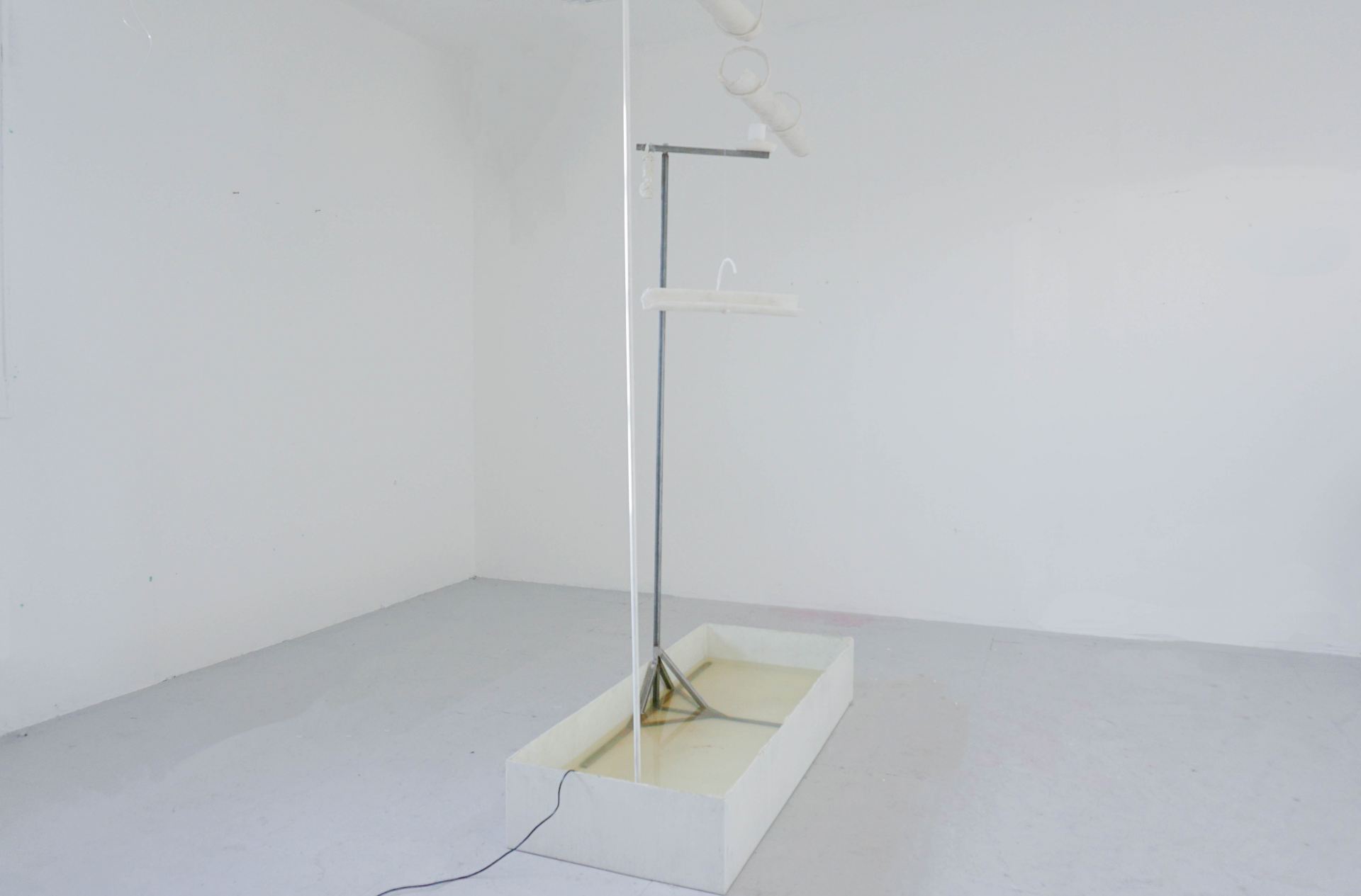 A sculptural water feature made using wax tubes standing in a white room.