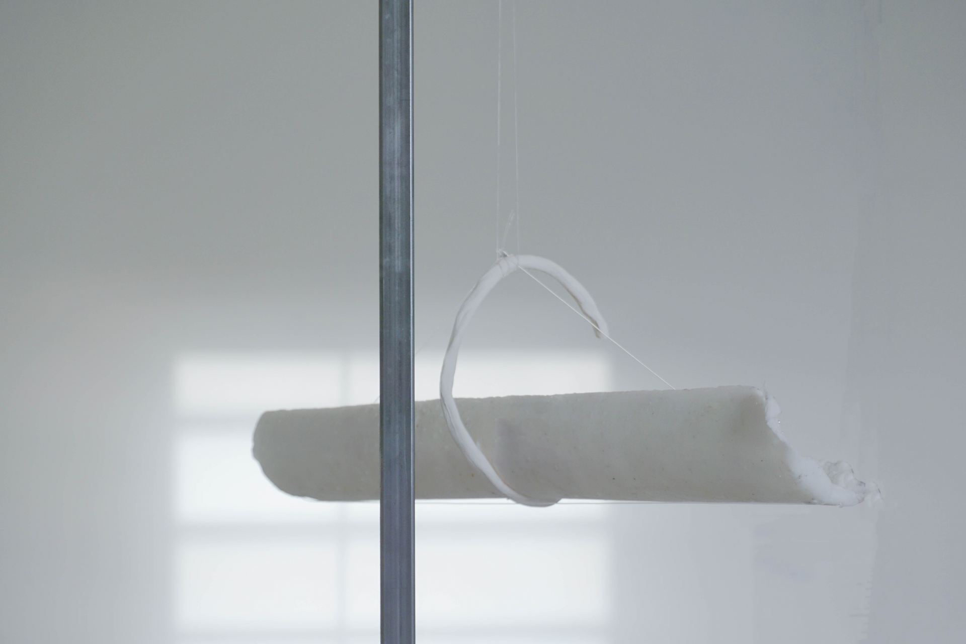 A detail shot of a sculptural water feature made using wax tubes standing in a white room.