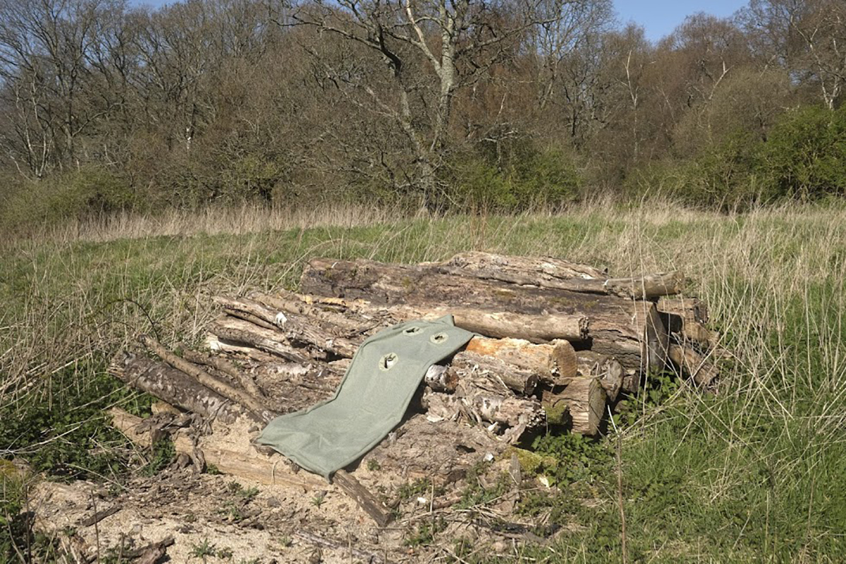 A khaki sculpture lying on top of a pile of logs.