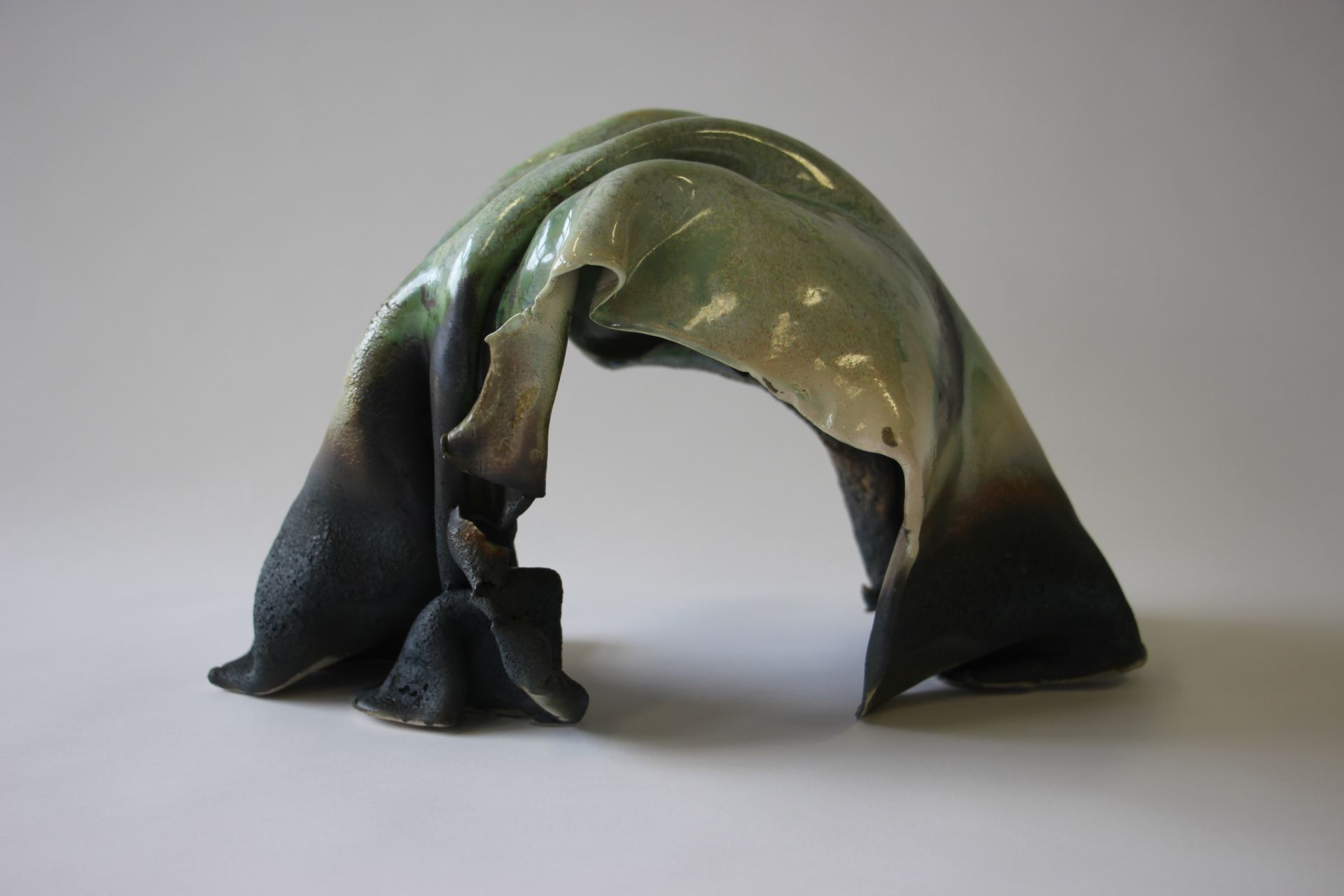 A photo of an abstract sculpture of an arch in green and black.