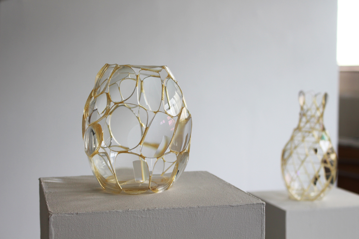 Twi vases made from gold-rimmed glasses standing on plinths.