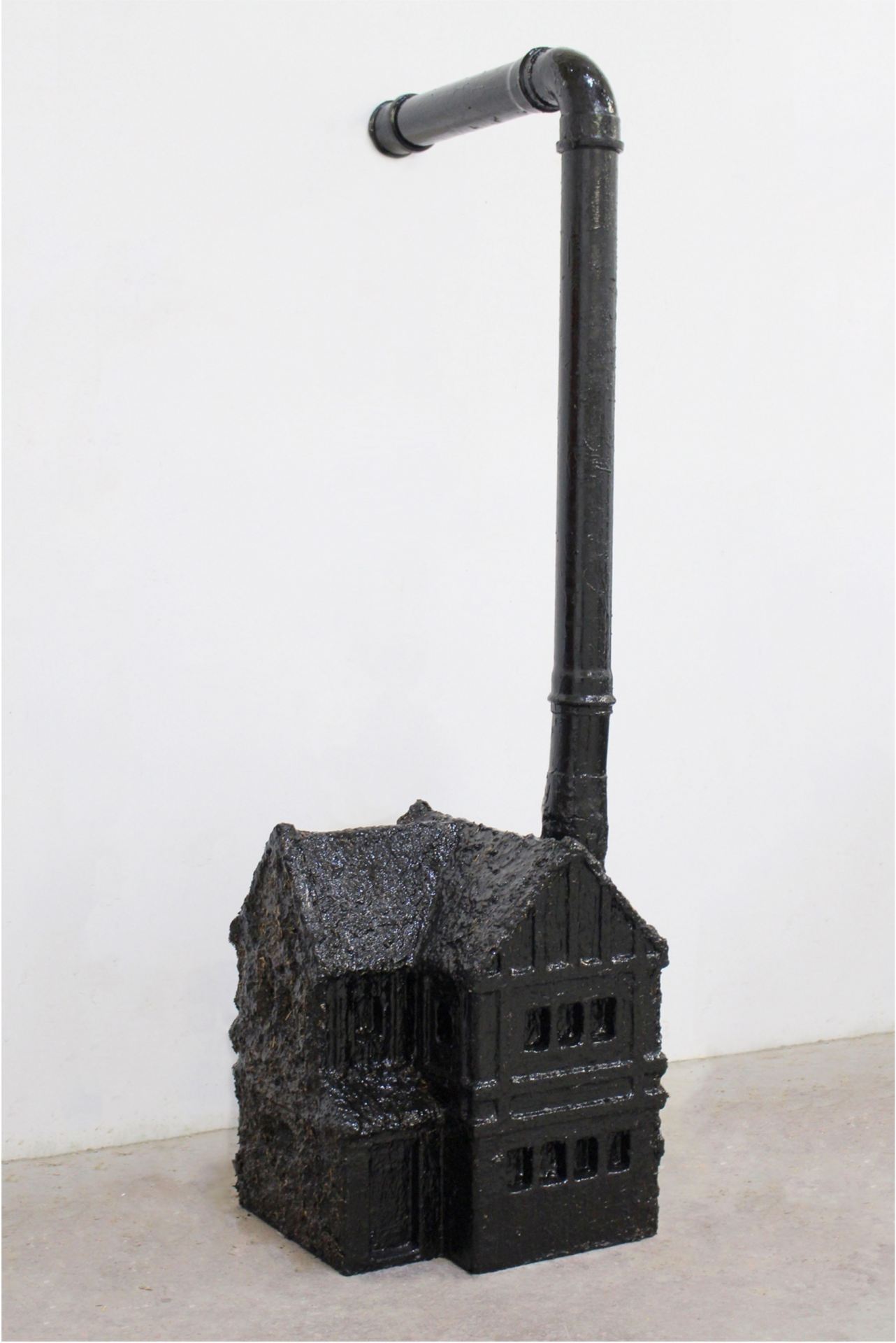 A small model of a black house with a drainpipe emerging from where it's chimney should be.