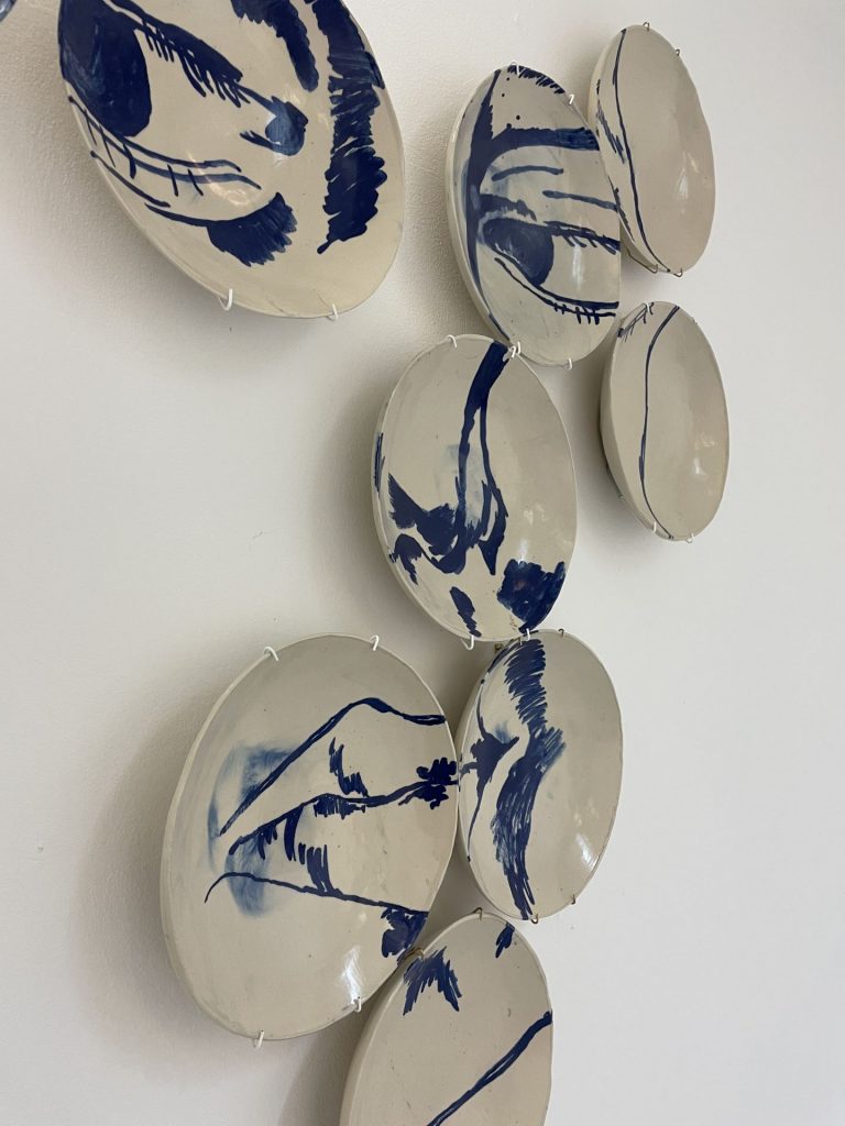 A photo of 9 plates hanging on a wall, which constitute an image of a face.
