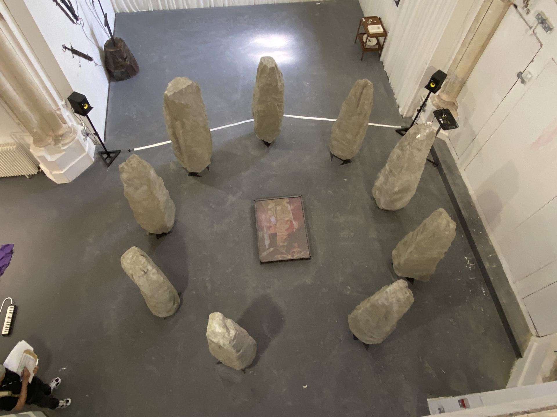 9 Standing stones surround a lightbox picturing an abstract image.