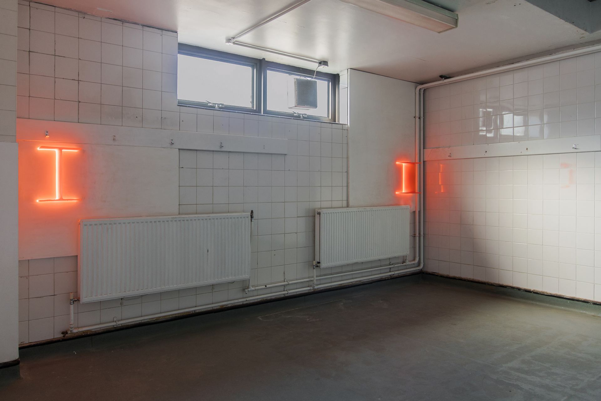 Installation views of glowing red I-beams perming the walls of a bathroom.