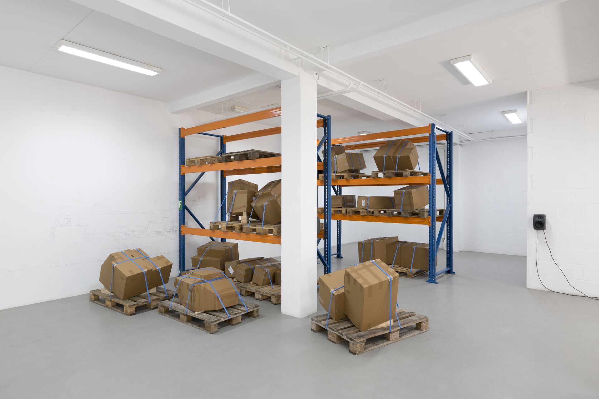 Installation shots of a room fitted with shelves and decorated with cardboard boxes on pallets.