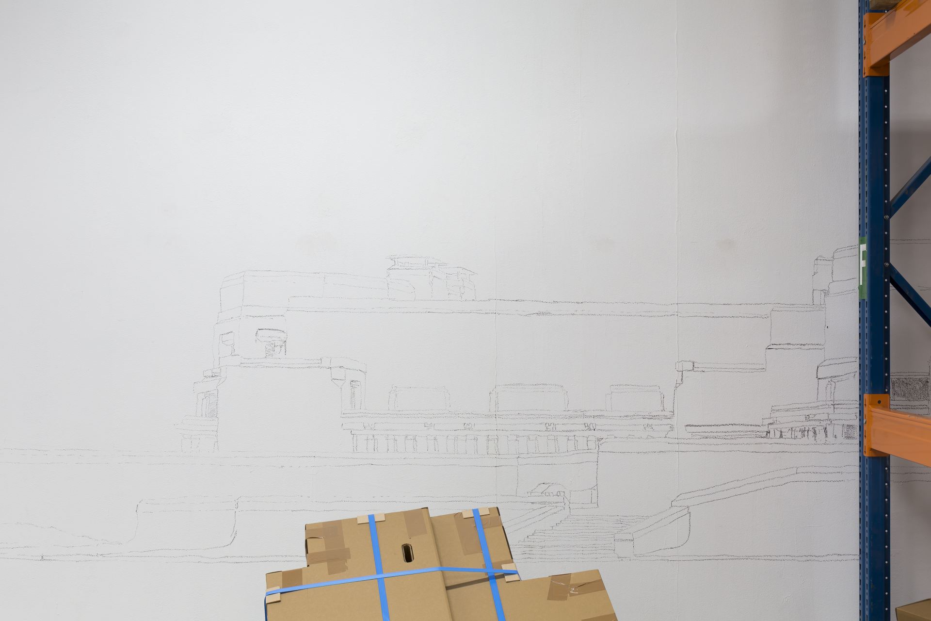 Installation shots of a room fitted with shelves and decorated with cardboard boxes on pallets.