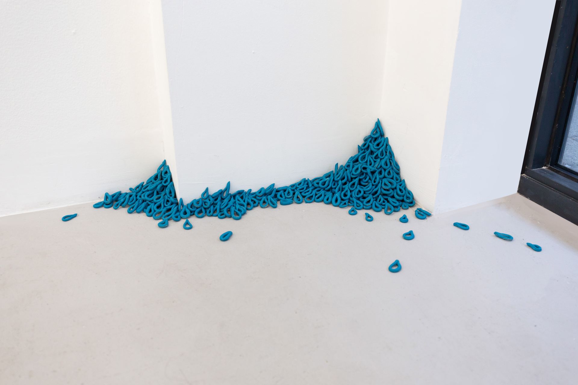 An image of many blue objects that look like teardrops, in two corners of an installation.