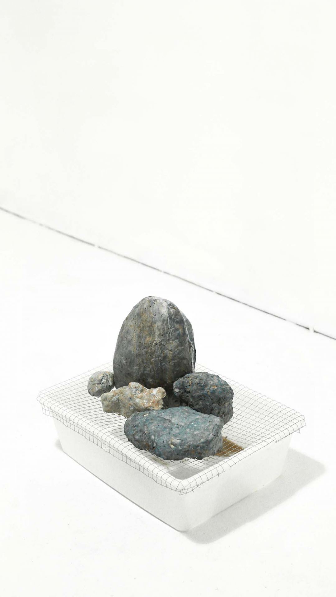 Shots of an installation featuring several rocks in a white space.