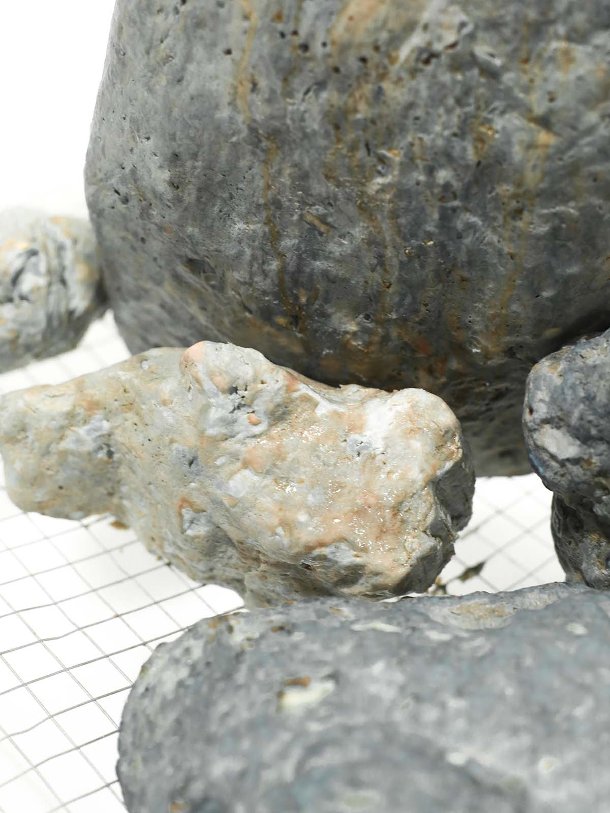 Shots of an installation featuring several rocks in a white space.