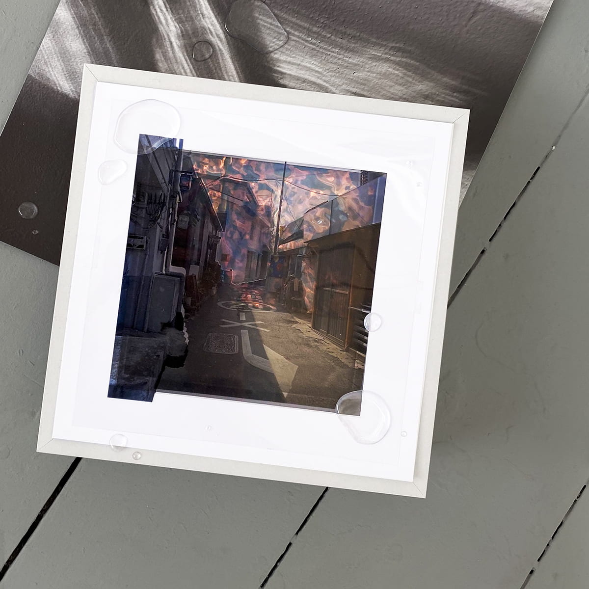 An image of a street in a white, square frame on a grey floor.
