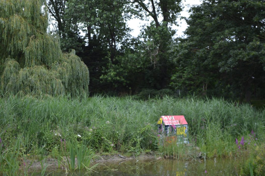 Photography of an installation at Folkstone Gardens of a house made out of Let by/For sale advertisement boards