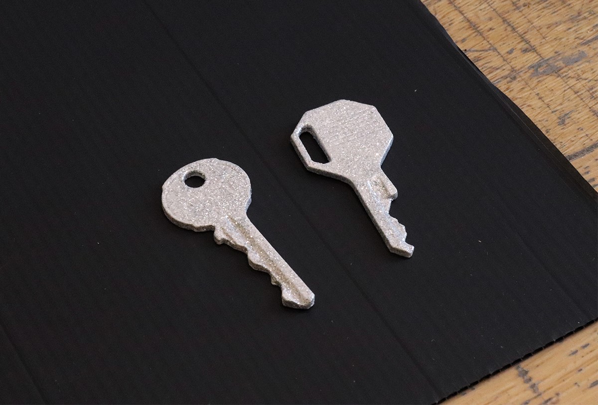 Two glittery casts of keys on top of a sheet of black corrugated board.
