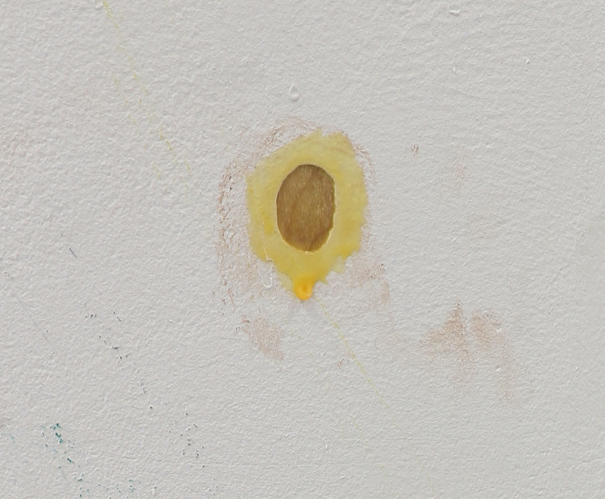 An image of some chipped paint on a white wall, with some yellow painted around it.