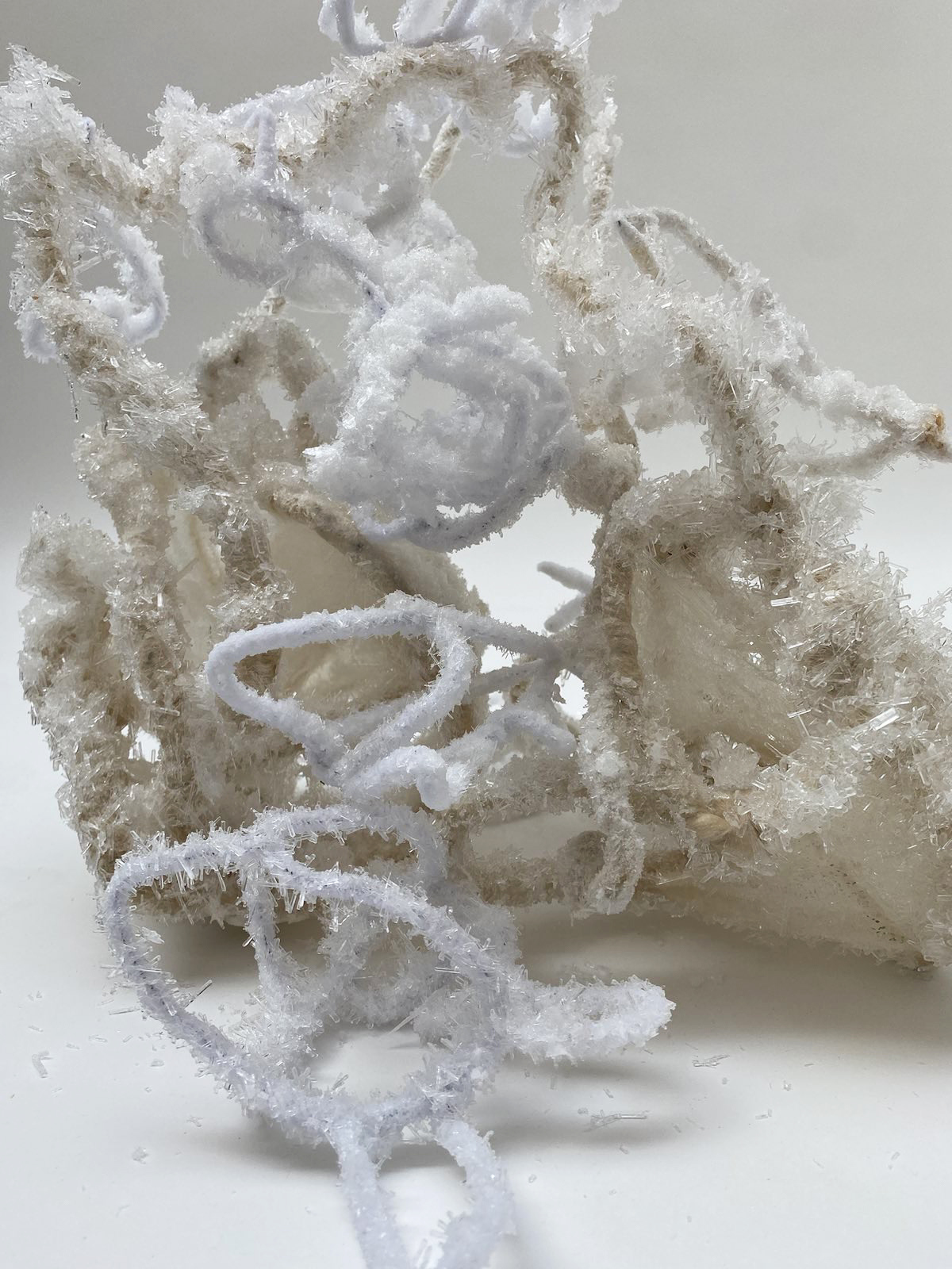 An image of a white and beige intertwined mass covered in large needle salt crystals.