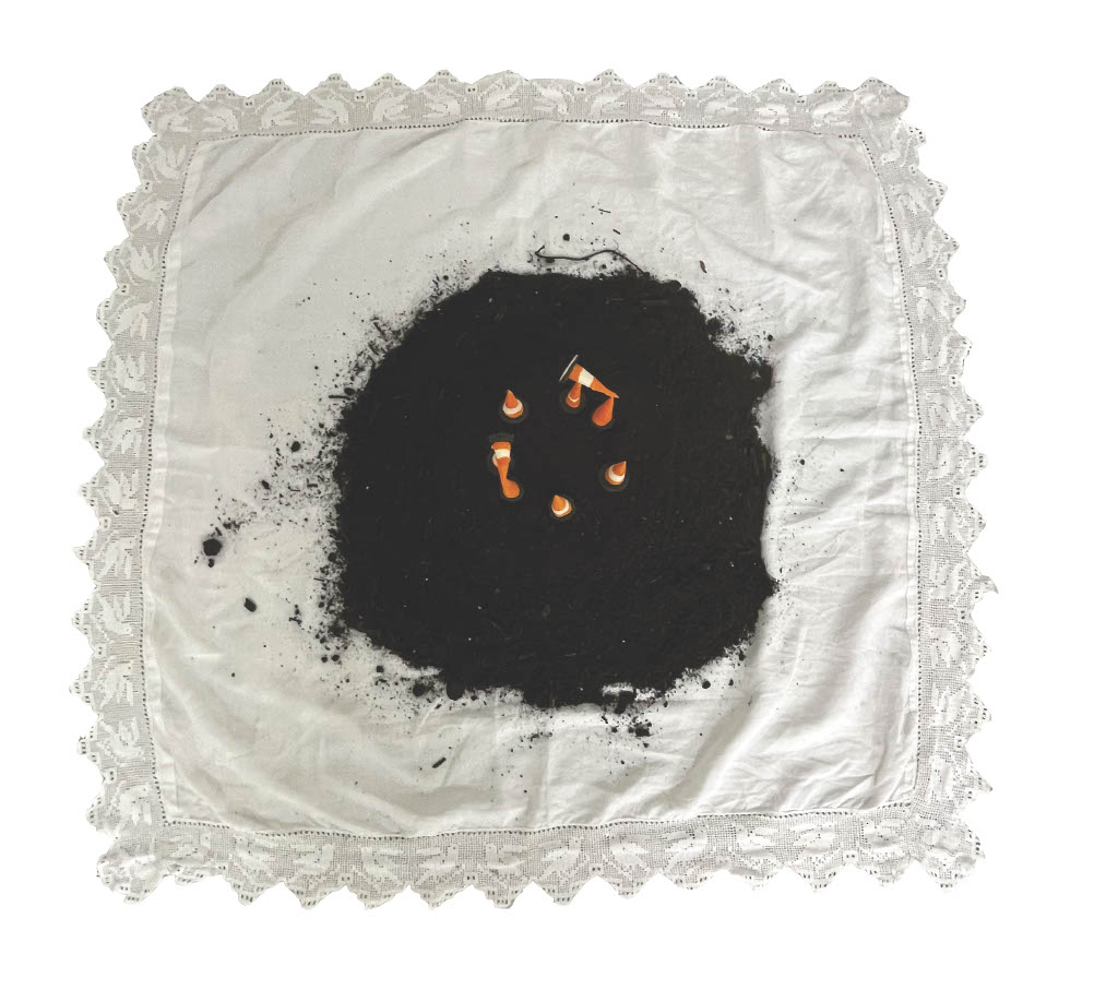 A bird's eye image of several cones in a circle on a mound of dirt on a white handkerchief.