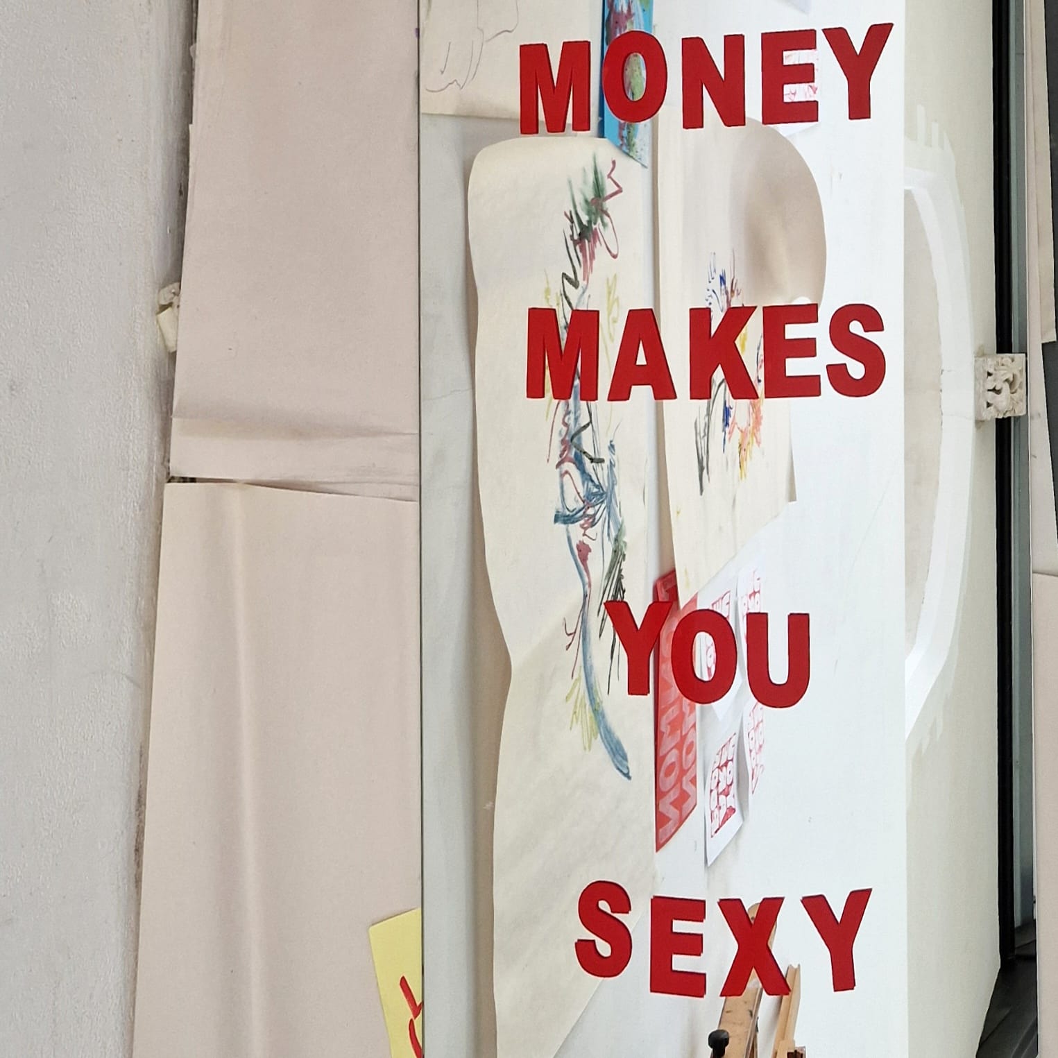 A collection of drawings mirrors and posters surrounding a room, one mirror says having money makes you sexy. 