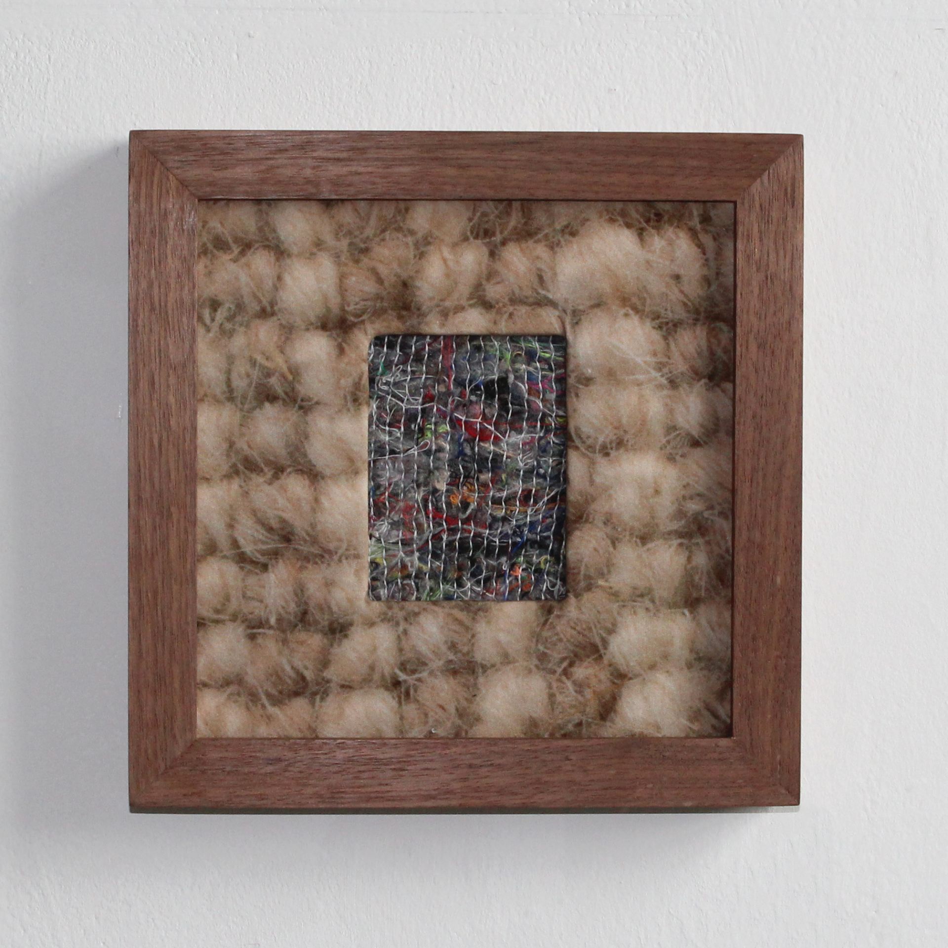 A square wooden frame framing a piece of transit blanket within another piece of fabric.