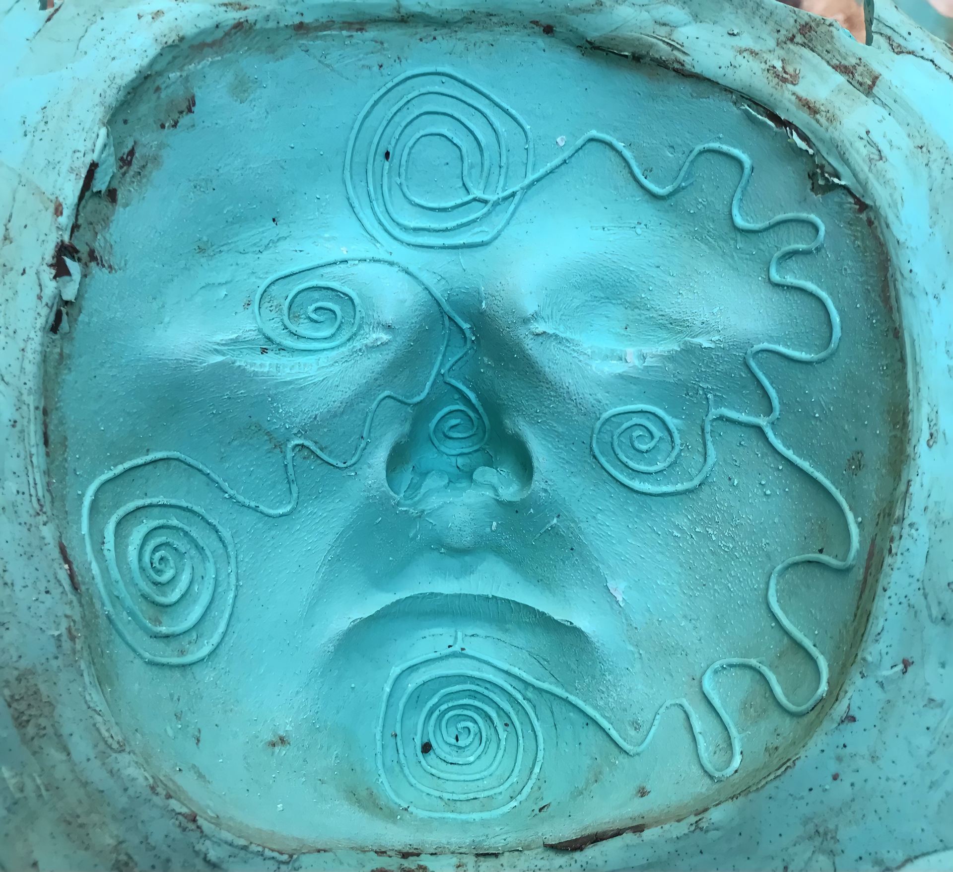 An image of a flattened, blue face covered in an indented spiral pattern.