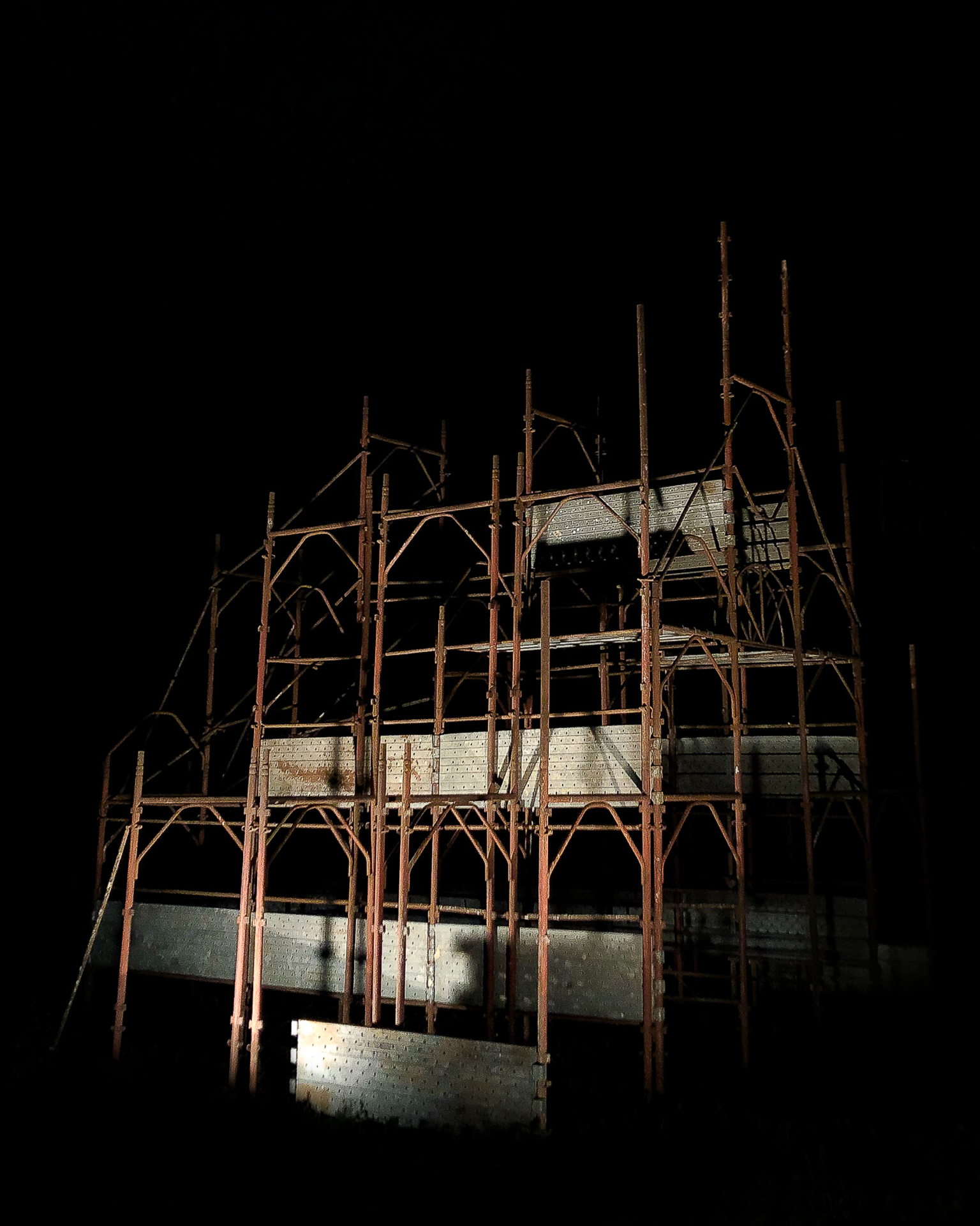 Documentation of a cathedral made from brown scaffolding, against a black background.