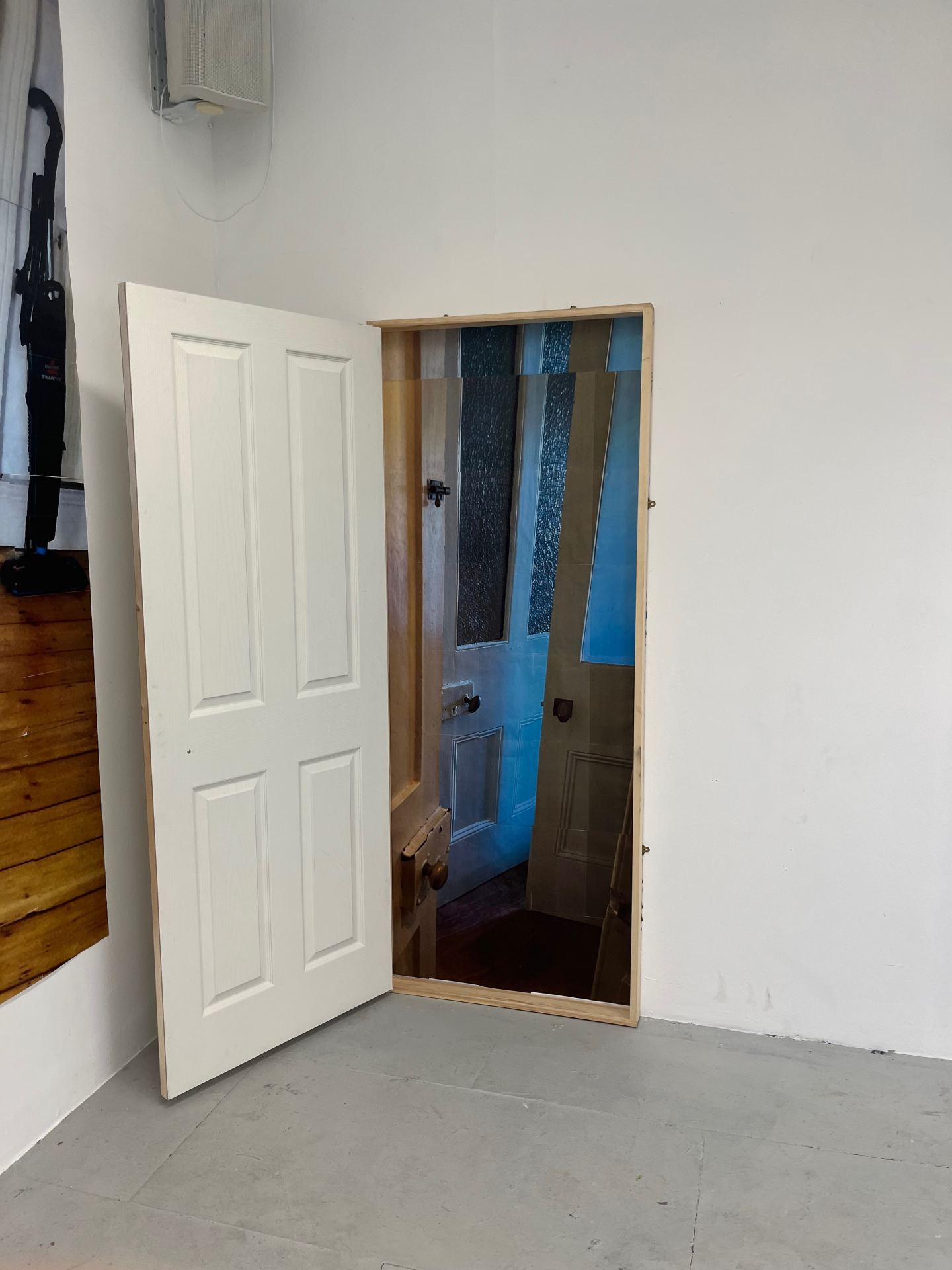 A 4-metre image constructed on the wall, layered with a still projection of an ikea bed, and a door mounted to the wall opening onto an image of multiple identical doors opening in on eachother.