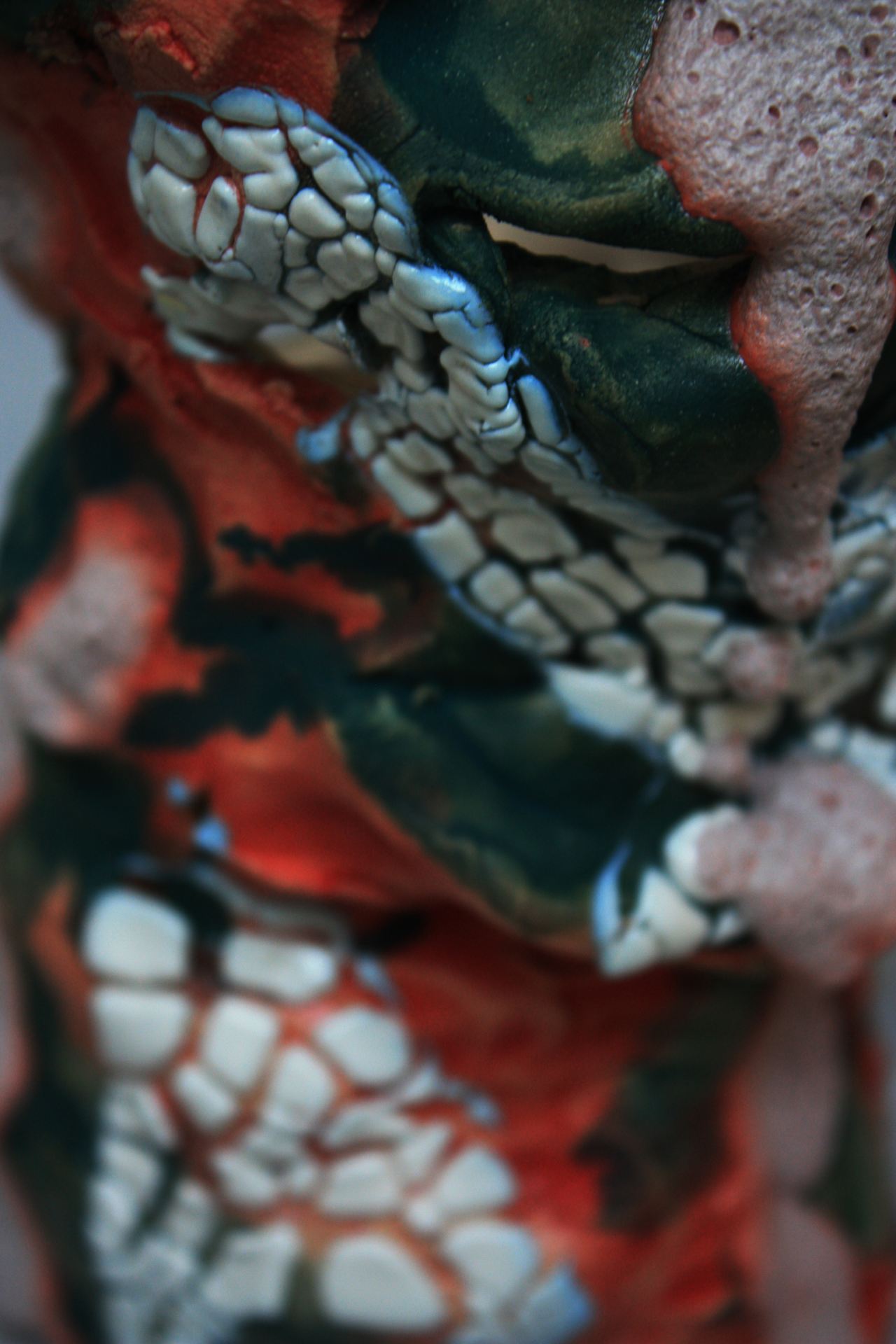 A close-up detail shot of a red, white and black ceramic object.