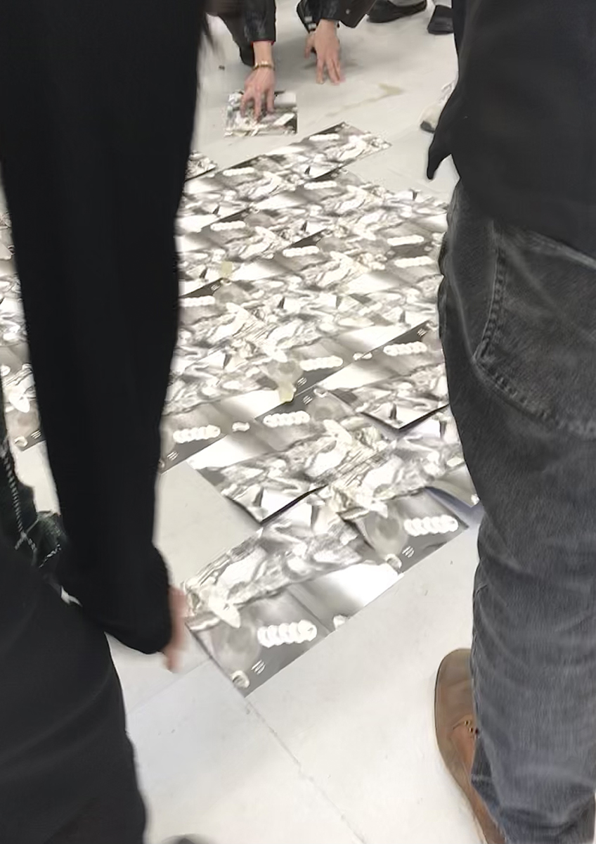 An image of viewers gathered tessellating, abstract images placed on a grey floor.