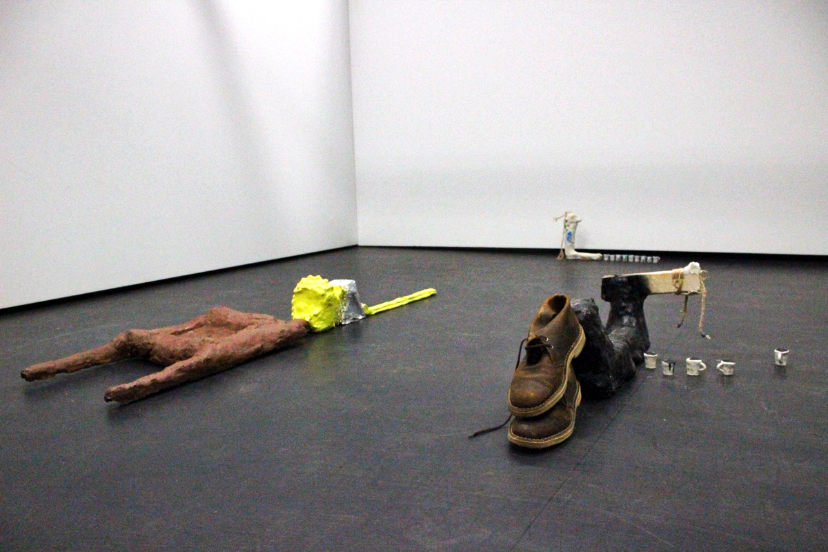 A photo of a sculpture made from various found objects, set against a black floor.