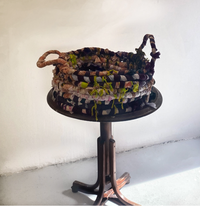 An image of a handmade fabric basket sitting on a round, wooden table.