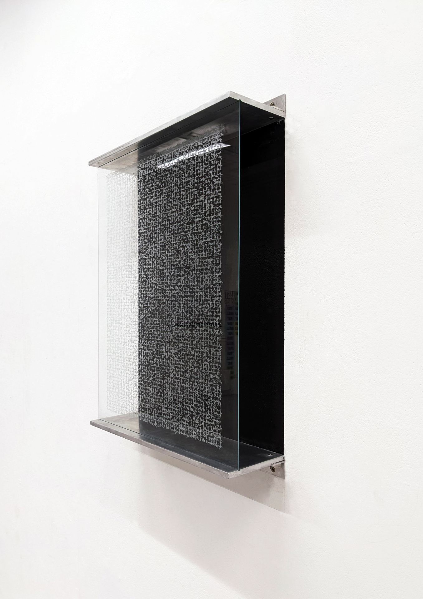 An image of a black object with a glass front, mounted on a white wall.
