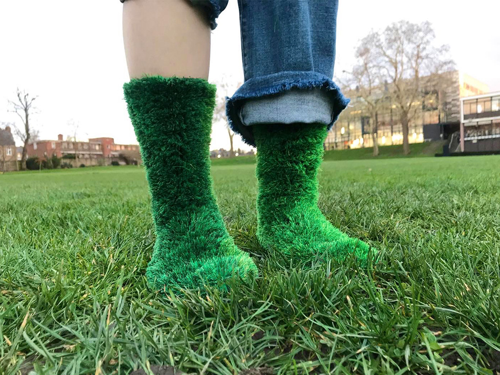 An image of someone wearing grass-printed socks, standing on a patch of grass.