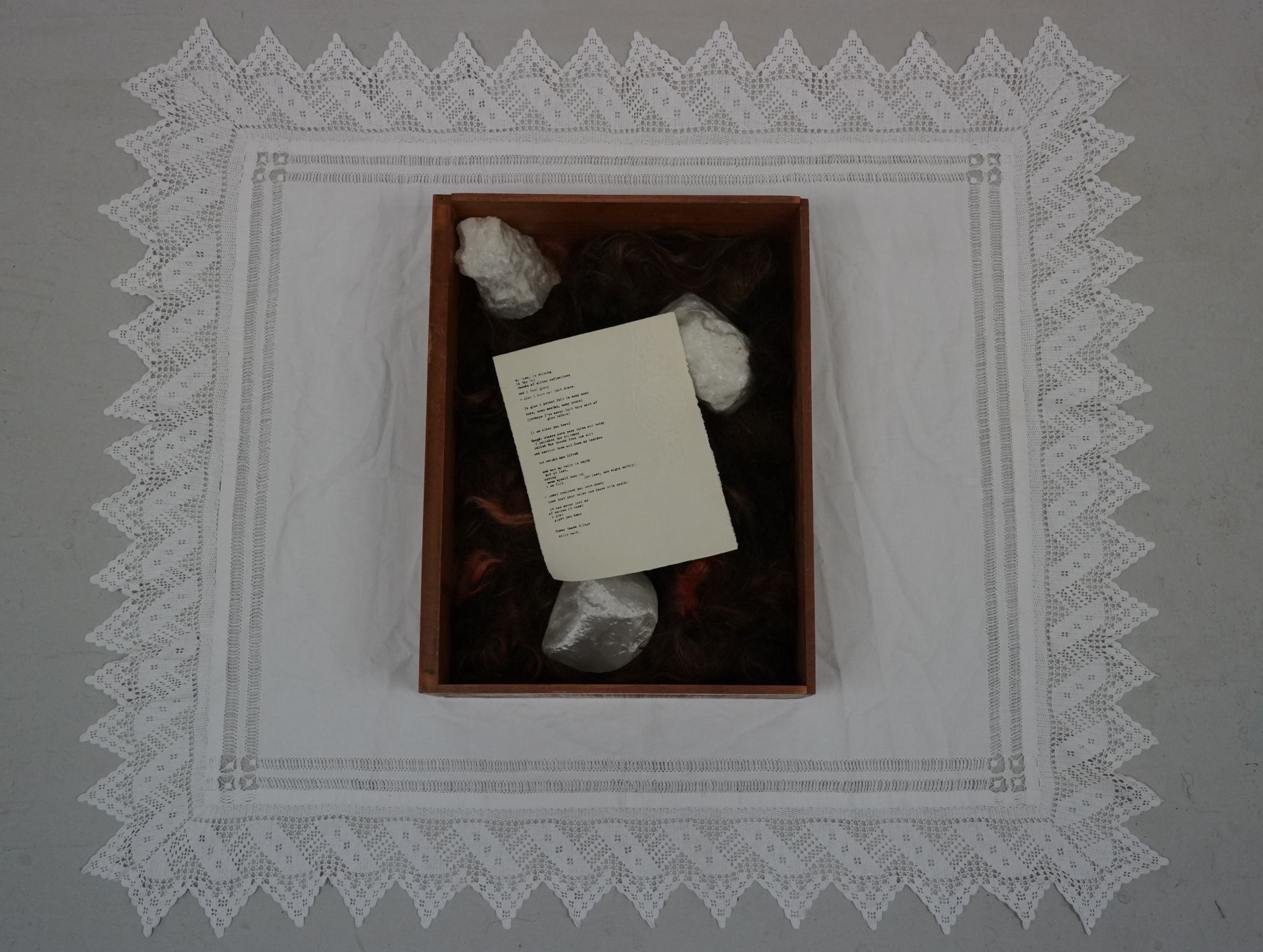 A bird's eye view of a box containing 3D printed stones and a handwritten note.