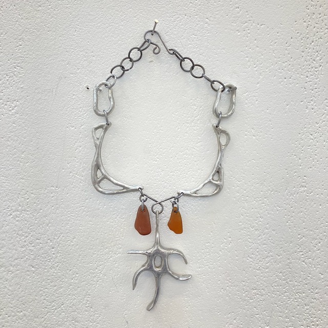 An image of an amulet with two red stones hanging on a white wall.
