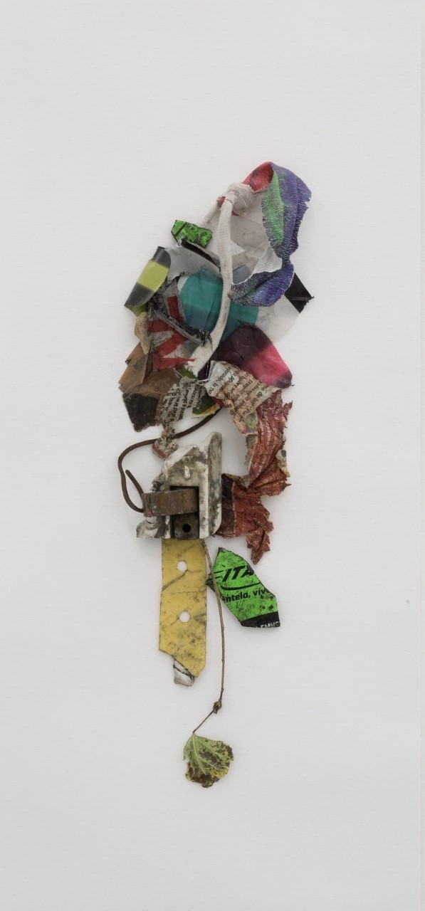 An image of a wall mounted sculpture made from found fabric and leaves, set against a white background.