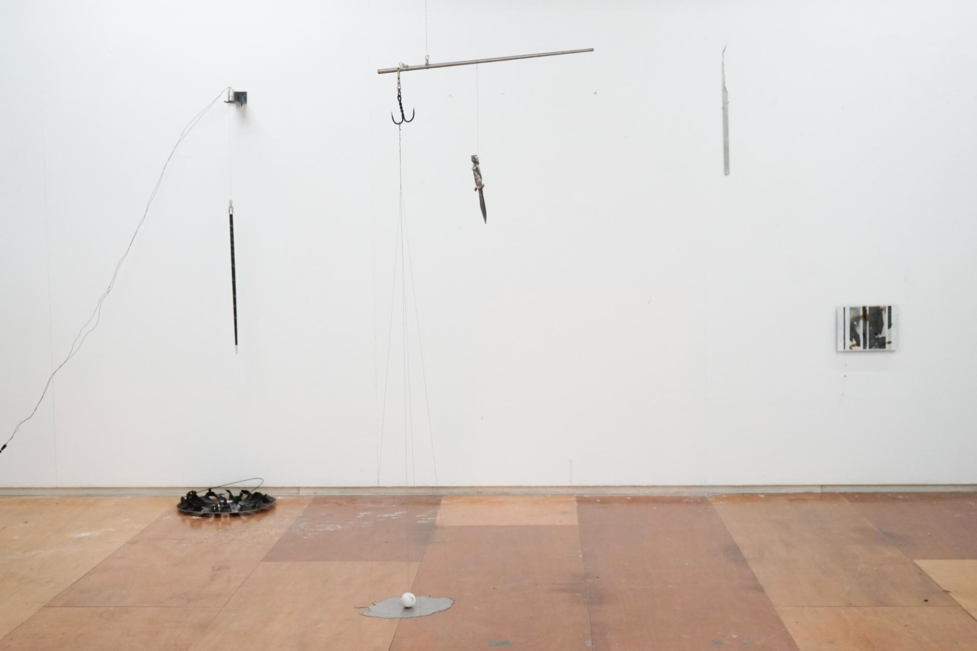 An installation view of several objects hanging from a white wall.