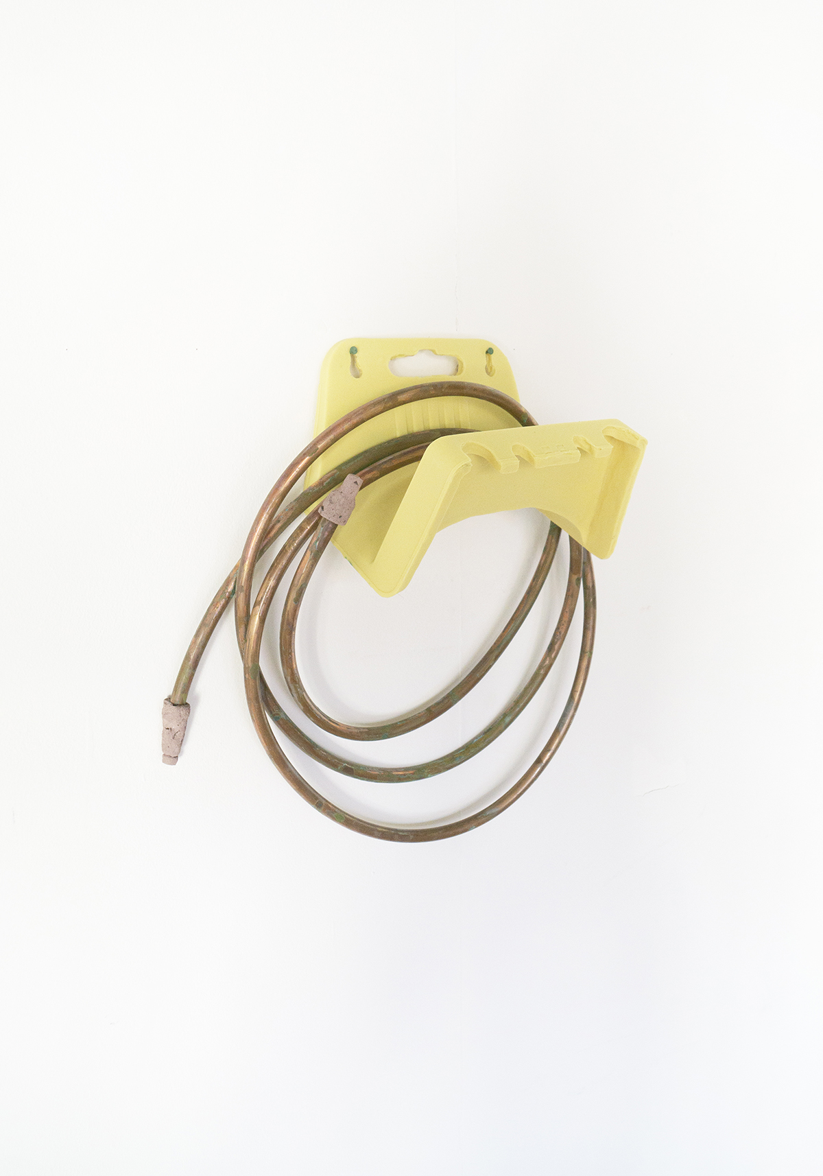 A rubber cast of a garden allotment hose holder with a copper hosepipe.
