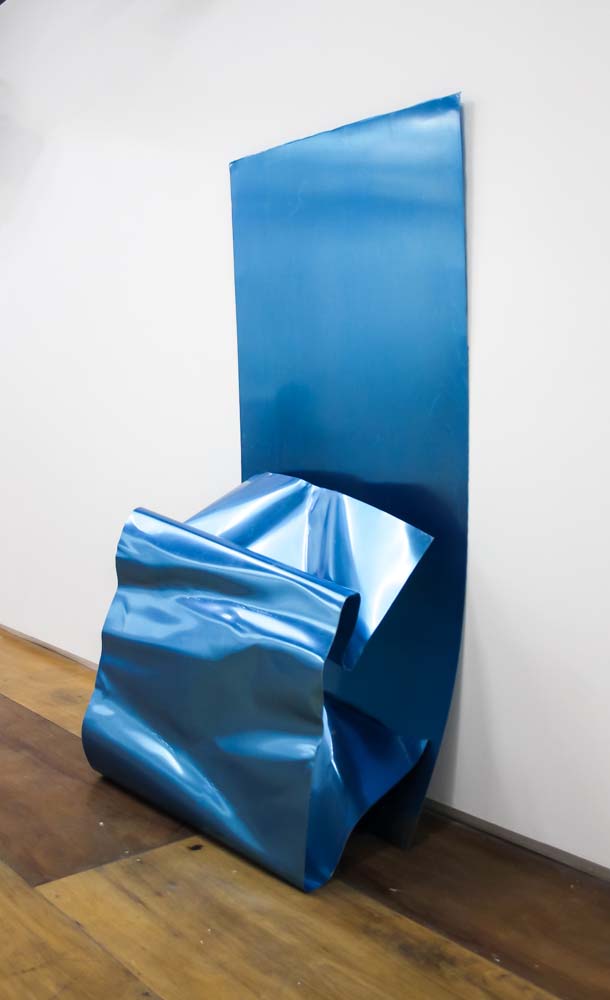 A blue, walll mounted sculpture made of folded metal.