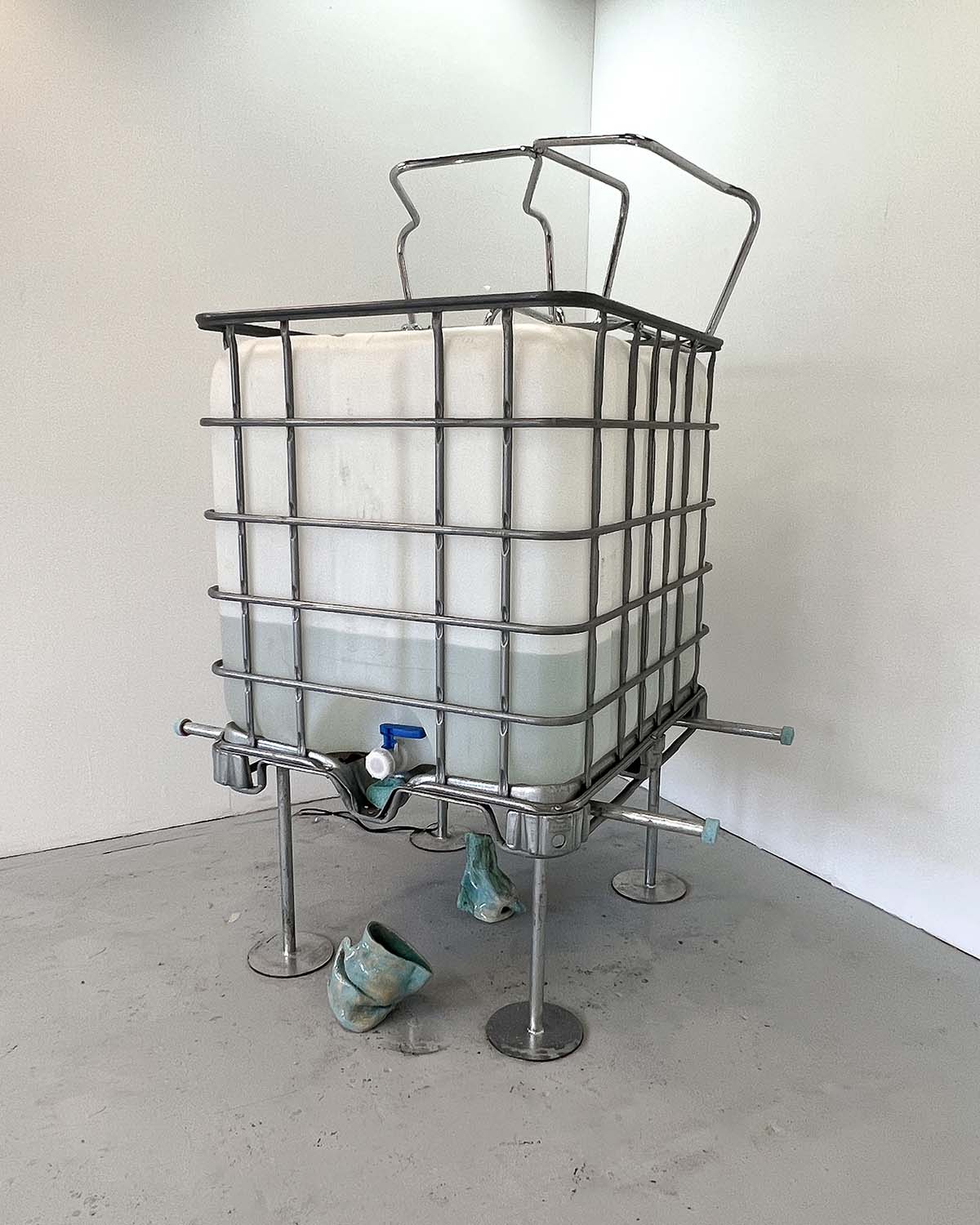 An image of a large plastic water container in a steel cage, standing on steel legs.