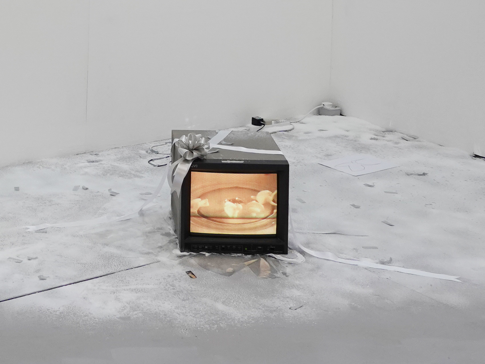 An image of a small monitor on a white floor depicting a fire.
