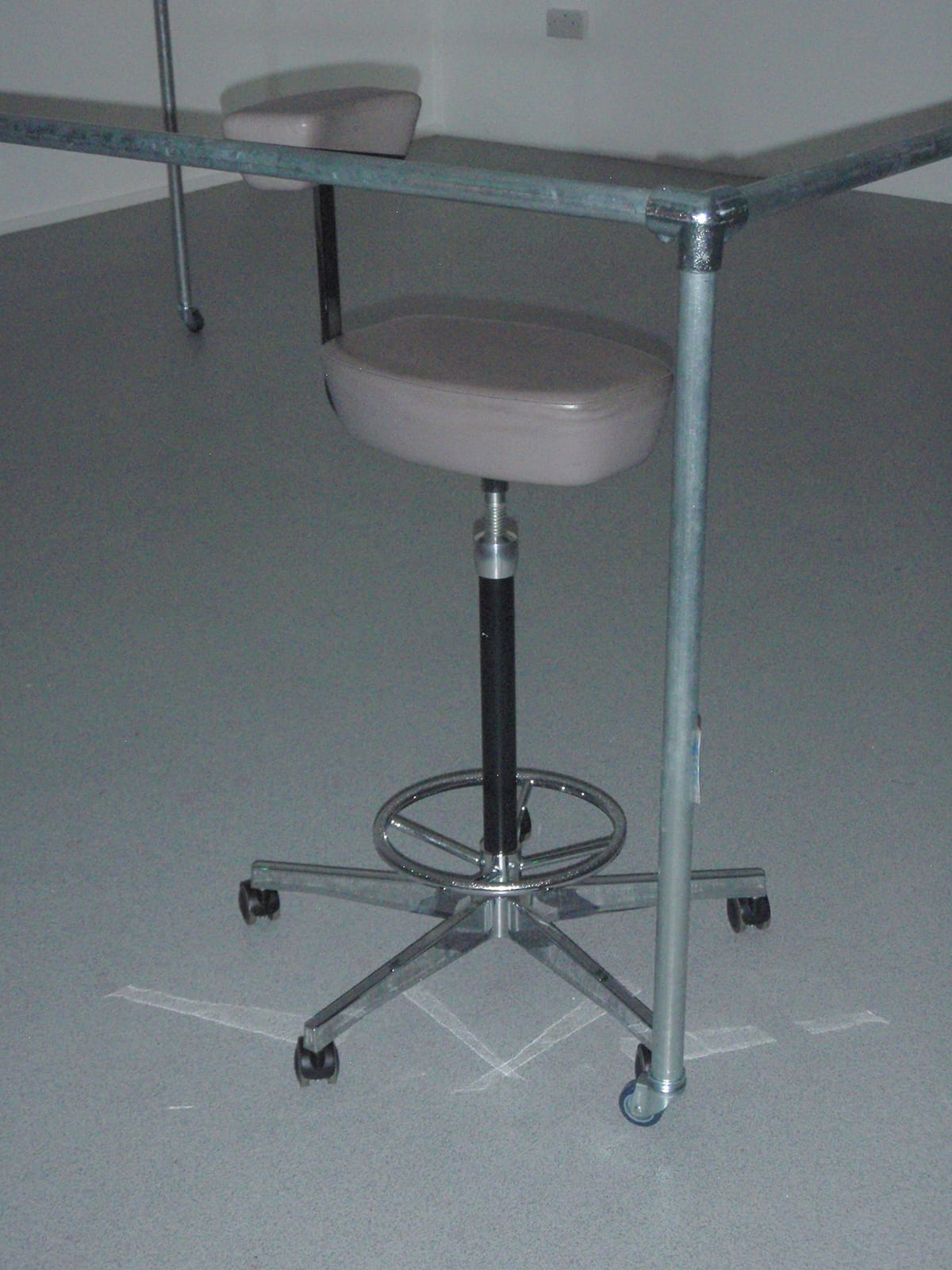 A flash photograph of a designer stool touching the edge of a metal frame
