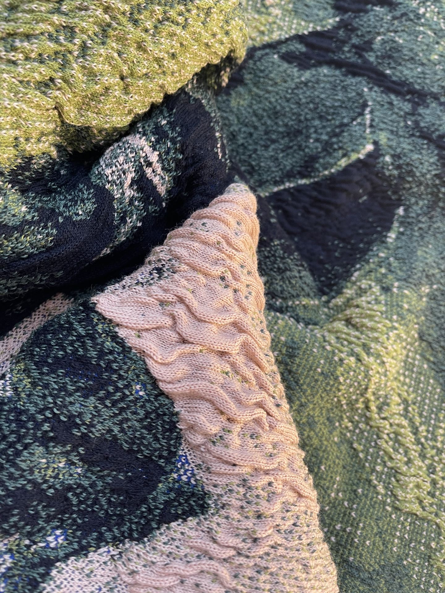 An image of a close up of a folded digital knit in green and pink.